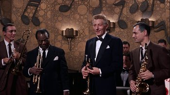 Movie still from “The Five Pennies” (1959), directed by Melville Shavelson – A man in a tuxedo is holding a glass of champagne; Medium shot, High angle
