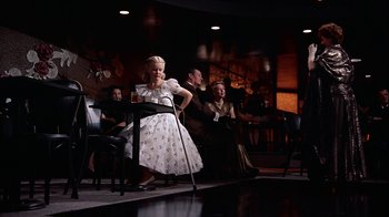 Movie still from “The Five Pennies” (1959), directed by Melville Shavelson – A group of people sitting around a room; Wide shot, Low angle