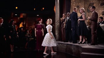 Movie still from “The Five Pennies” (1959), directed by Melville Shavelson – A little girl wearing a white dress standing on a stage; Wide shot, High angle