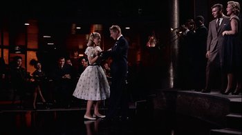 Movie still from “The Five Pennies” (1959), directed by Melville Shavelson – A man and a woman standing next to each other on a stage; Wide shot, Low angle