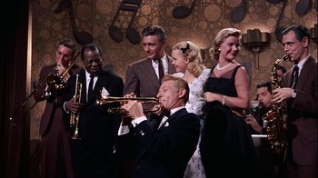 Movie still from “The Five Pennies” (1959), directed by Melville Shavelson – A group of people that are standing around a trumpet; Medium shot, High angle