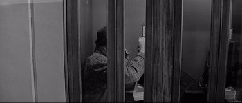 Movie still from “The Fortune Cookie” (1966), directed by Billy Wilder – A man sitting in a cell looking at a cell phone; Medium shot, Overhead angle