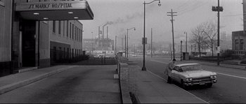 Movie still from “The Fortune Cookie” (1966), directed by Billy Wilder – A black - and - white photo of a city street with smoke billowing from the chimney; Extreme Wide shot, Over the shoulder angle
