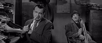 Movie still from “The Fortune Cookie” (1966), directed by Billy Wilder – An older man smoking a cigarette in front of another older man; Medium shot, Over the shoulder angle