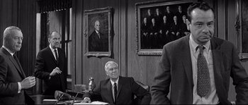 Movie still from “The Fortune Cookie” (1966), directed by Billy Wilder – An older man sitting at a desk in front of a painting; Medium shot, Over the shoulder angle