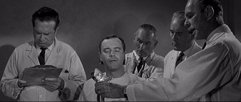 Movie still from “The Fortune Cookie” (1966), directed by Billy Wilder – An old photo of a man getting his head shaved; Medium shot, Low angle