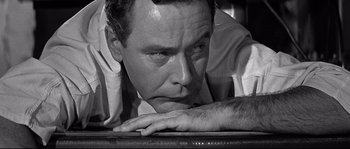 Movie still from “The Fortune Cookie” (1966), directed by Billy Wilder – Black and white photograph of a man leaning on a desk; Close Up shot, High angle