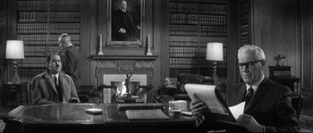 Movie still from “The Fortune Cookie” (1966), directed by Billy Wilder – A man sitting at a desk in a library; Medium shot, Over the shoulder angle