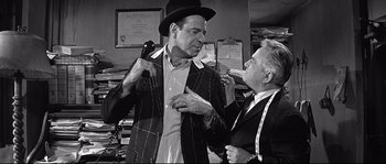 Movie still from “The Fortune Cookie” (1966), directed by Billy Wilder – A man in a top hat and a man in a suit; Medium shot, Over the shoulder angle
