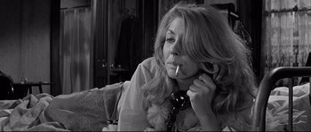 Movie still from “The Fortune Cookie” (1966), directed by Billy Wilder – A woman smoking a cigarette while sitting on a couch; Close Up shot, Low angle