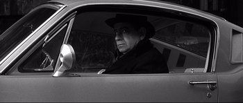 Movie still from “The Fortune Cookie” (1966), directed by Billy Wilder – A black and white photo of a man sitting in the driver's seat of a car; Medium shot, High angle