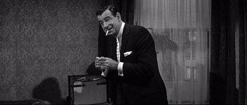 Movie still from “The Fortune Cookie” (1966), directed by Billy Wilder – A black and white photo of a man smoking a cigarette; Medium shot, Over the shoulder angle