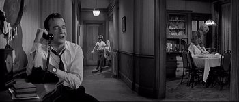 Movie still from “The Fortune Cookie” (1966), directed by Billy Wilder – A man and a woman sitting on a skateboard in a hallway; Medium shot, Over the shoulder angle