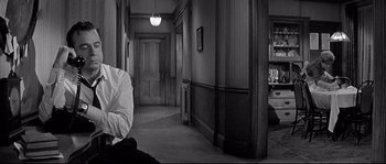 Movie still from “The Fortune Cookie” (1966), directed by Billy Wilder – A black and white photo of a man sitting in front of a door; Medium shot, High angle