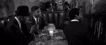 Movie still from “The Fortune Cookie” (1966), directed by Billy Wilder – A black and white photo of people sitting at a table; Medium shot, Over the shoulder angle