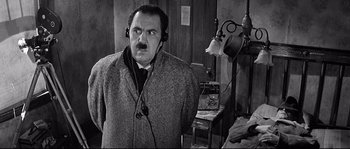 Movie still from “The Fortune Cookie” (1966), directed by Billy Wilder – A man with a mustache wearing headphones in a room; Medium shot, High angle