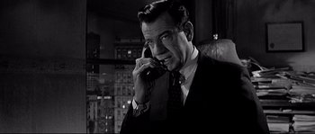 Movie still from “The Fortune Cookie” (1966), directed by Billy Wilder – A man talking on a phone while wearing a suit and tie; Close Up shot, Low angle