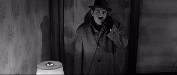 Movie still from “The Fortune Cookie” (1966), directed by Billy Wilder – A man in a hat and coat talking on a phone; Medium shot, High angle