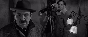 Movie still from “The Fortune Cookie” (1966), directed by Billy Wilder – Two men are standing in front of a video camera; Medium shot, Over the shoulder angle