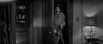 Movie still from “The Fortune Cookie” (1966), directed by Billy Wilder – An old photo of a man standing in a door way; Medium shot, Over the shoulder angle