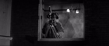 Movie still from “The Fortune Cookie” (1966), directed by Billy Wilder – A black and white photo of a man looking through a telescope; Medium shot, High angle