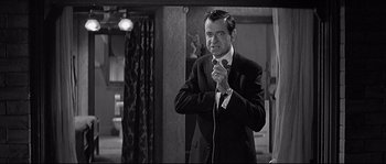 Movie still from “The Fortune Cookie” (1966), directed by Billy Wilder – A black and white photo of a man in a suit and tie; Medium shot, Over the shoulder angle