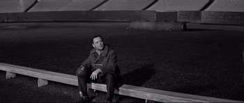 Movie still from “The Fortune Cookie” (1966), directed by Billy Wilder – A man sitting on top of a bench in a field; Medium shot, Low angle