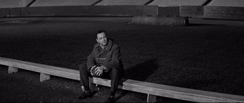 Movie still from “The Fortune Cookie” (1966), directed by Billy Wilder – A black and white photo of a man sitting on a bench; Medium shot, High angle
