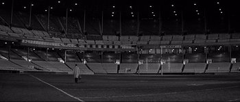 Movie still from “The Fortune Cookie” (1966), directed by Billy Wilder – A man walking across a soccer field in a stadium; Extreme Wide shot, High angle