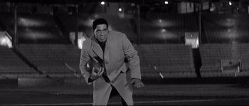 Movie still from “The Fortune Cookie” (1966), directed by Billy Wilder – A black and white photo of a man throwing a football; Medium shot, Low angle