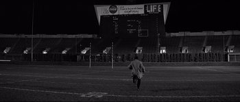 Movie still from “The Fortune Cookie” (1966), directed by Billy Wilder – A man running across a football field at night; Wide shot, High angle