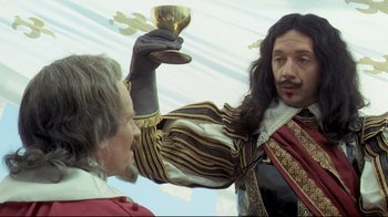 Movie still from “The Four Musketeers: Milady's Revenge” (1974), directed by Richard Lester – Two men dressed in renaissance clothing , one holding a trophy; Medium shot, Low angle