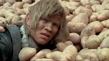 Movie still from “The Four Musketeers: Milady's Revenge” (1974), directed by Richard Lester – A man in a pile of potatoes; Close Up shot, Overhead angle