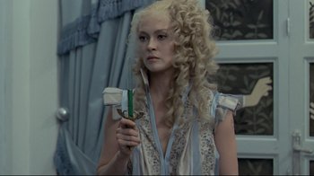 Movie still from “The Four Musketeers: Milady's Revenge” (1974), directed by Richard Lester – A woman with long blonde curly hair holding a knife; Medium shot, Over the shoulder angle