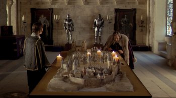 Movie still from “The Four Musketeers: Milady's Revenge” (1974), directed by Richard Lester – Two men are standing in front of a castle cake; Wide shot, High angle