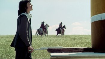 Movie still from “The Four Musketeers: Milady's Revenge” (1974), directed by Richard Lester – A man standing in a field holding a baseball bat; Medium shot, Low angle