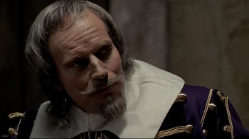 Movie still from “The Four Musketeers: Milady's Revenge” (1974), directed by Richard Lester – An old man with a beard and a mustache; Close Up shot, Over the shoulder angle