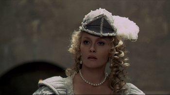 Movie still from “The Four Musketeers: Milady's Revenge” (1974), directed by Richard Lester – A woman in a white and black dress with a hat; Close Up shot, Over the shoulder angle