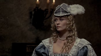 Movie still from “The Four Musketeers: Milady's Revenge” (1974), directed by Richard Lester – A woman in a white and blue dress with a feather hat; Medium shot, Over the shoulder angle