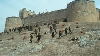 Movie still from “The Four Musketeers: Milady's Revenge” (1974), directed by Richard Lester – A group of men in fatigues are running in the sand; Extreme Wide shot, High angle