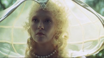 Movie still from “The Four Musketeers: Milady's Revenge” (1974), directed by Richard Lester – A woman with blonde curly hair wearing a pearl necklace; Close Up shot, Low angle
