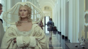 Movie still from “The Four Musketeers: Milady's Revenge” (1974), directed by Richard Lester – A woman in a white dress standing in a hallway; Medium shot, Over the shoulder angle