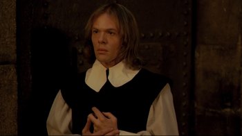 Movie still from “The Four Musketeers: Milady's Revenge” (1974), directed by Richard Lester – A man with long blonde hair wearing a black and white shirt; Medium shot, High angle