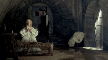 Movie still from “The Four Musketeers: Milady's Revenge” (1974), directed by Richard Lester – A woman in a white dress sitting on a bench in front of a man; Wide shot, High angle