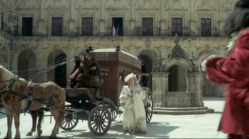 Movie still from “The Four Musketeers: Milady's Revenge” (1974), directed by Richard Lester – A man in a white robe standing in front of a horse drawn carriage; Wide shot, Low angle