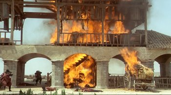 Movie still from “The Four Musketeers: Milady's Revenge” (1974), directed by Richard Lester – A fire is burning in the middle of a building; Extreme Wide shot, Low angle