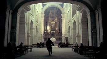Movie still from “The Four Musketeers: Milady's Revenge” (1974), directed by Richard Lester – A man walking through a large cathedral with a large arch; Extreme Wide shot, Low angle