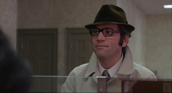 Movie still from “The Friends of Eddie Coyle” (1973), directed by Peter Yates – A man wearing a hat and glasses sitting in front of a window; Close Up shot, Low angle