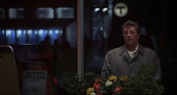 Movie still from “The Friends of Eddie Coyle” (1973), directed by Peter Yates – A man standing in front of a bunch of flowers; Medium shot, Over the shoulder angle
