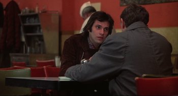 Movie still from “The Friends of Eddie Coyle” (1973), directed by Peter Yates – A man sitting in front of another man at a table; Medium shot, Over the shoulder angle